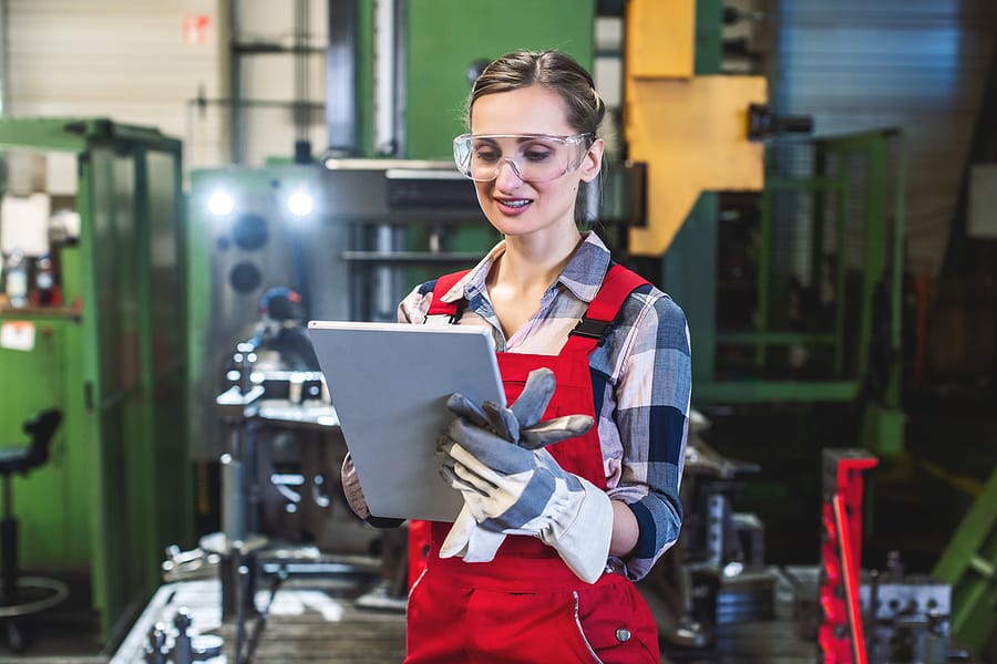 Medewerker met tablet op de werkvloer, digitaal verbonden met de productie