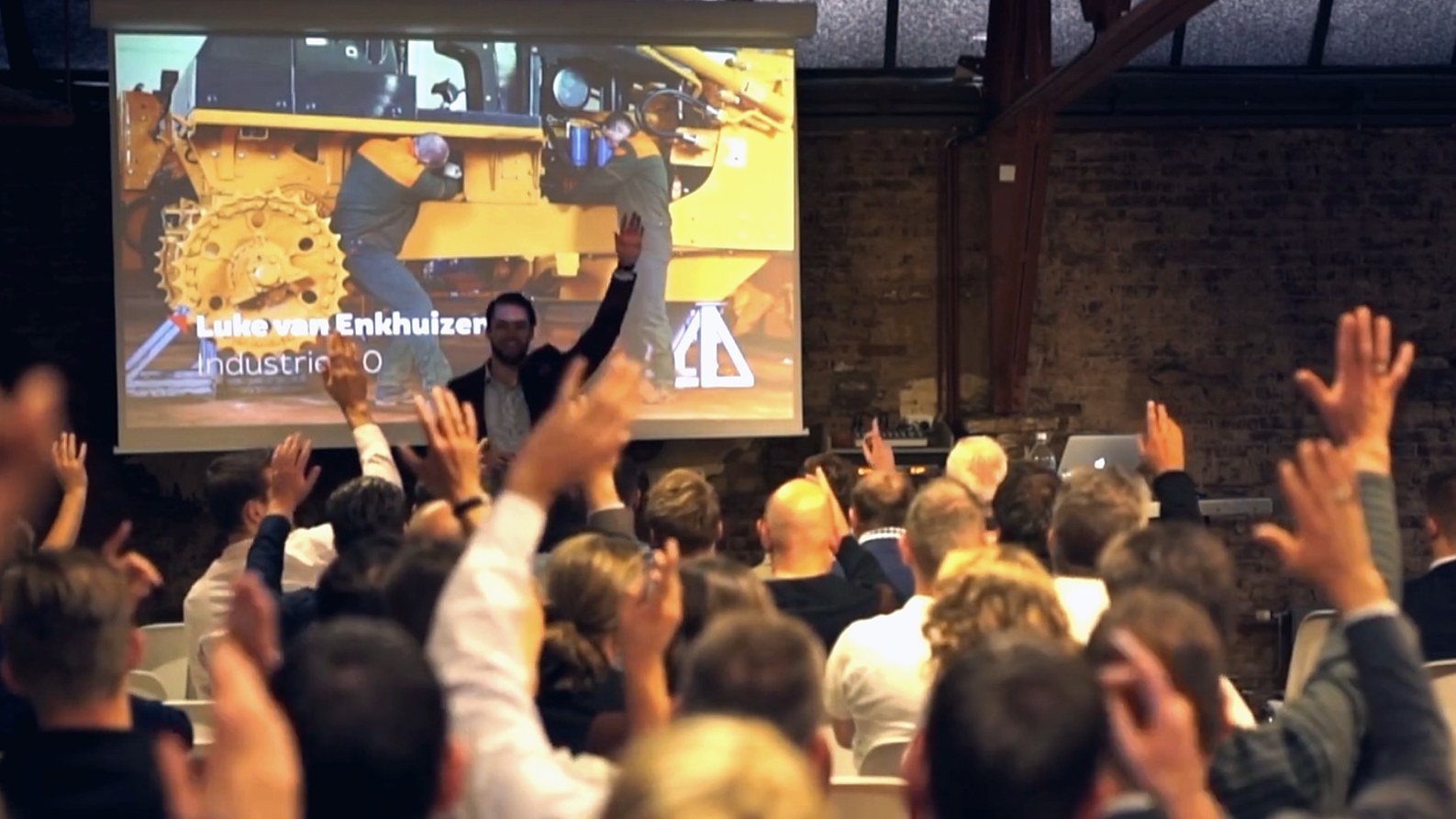 Luke op het podium, de zaal steekt massaal de handen op